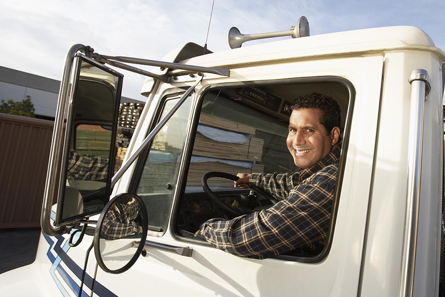 Business Insurance - Truck Driver Smiling in the Cab of a White Semi Truck